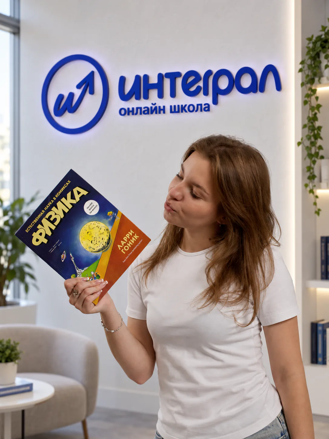 Преподаватель «Интеграла» с учебником физики в студии школы